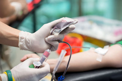 Cropped hands of doctor holding blood bag in hospital