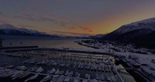 Scenic view of sea by snowcapped mountains against sky during sunset