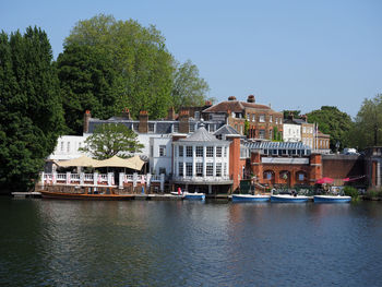 Buildings by river against sky