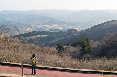 Rear view of traveler standing by mountains against sky