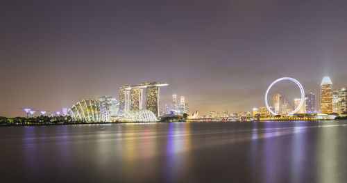 Illuminated city by river at night