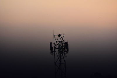 Silhouette communications tower against sky during sunset