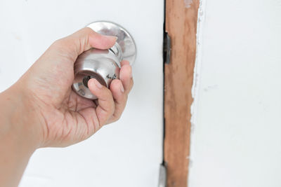 Close-up of hand holding white doorknob at home