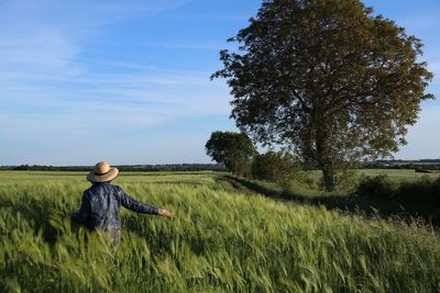 Rear view of woman on agricultural field against sky