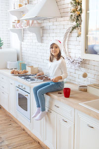 Portrait of smiling girl with tray sitting on kitchen counter