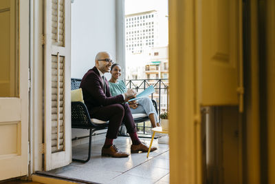 Smiling business coworkers sitting on sofa in balcony