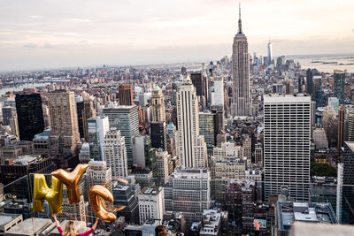 Rear view of woman holding alphabet balloons against empire state building in city