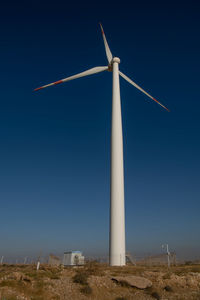 Low angle view of windmill on field against blue sky