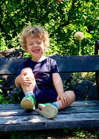 Happy boy sitting on bench in park