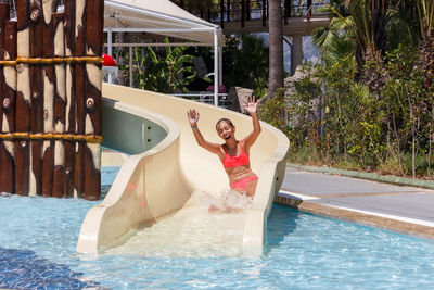 Happy woman in slide at pool