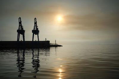 Silhouette ship in sea against sky during sunset