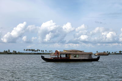 Boats in sea against cloudy sky