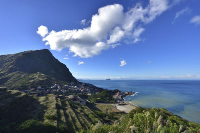 Scenic view of sea and mountains against blue sky