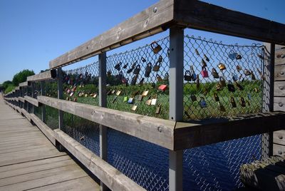 Love locks hanging on fence against sky