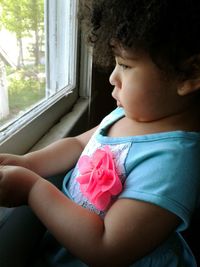 Close-up of cute girl sitting at window