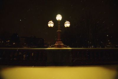 Illuminated street light against sky at night