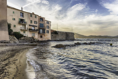 Buildings by sea against sky