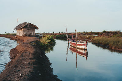 Wooden posts on lake by building against sky