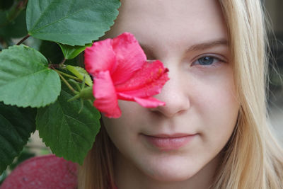 Close-up portrait of young woman by pink flower