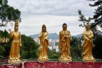 Statue against trees and plants against sky