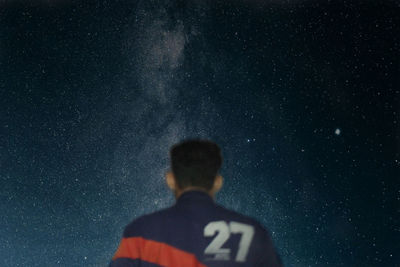 Rear view of man standing against sky at night