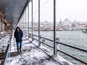 Man standing on bridge in city during winter