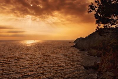 Scenic view of sea against cloudy sky at sunset