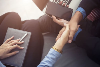 Midsection of colleagues handshaking in office