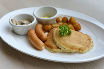 Close-up of pancakes with sausages served on table