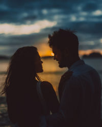 Couple kissing against sky during sunset