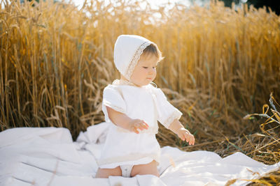 Sweet eight-month-old baby boy sitting on a blanket in a field