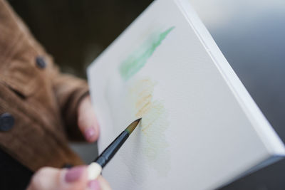 Woman standing at lakeside and drawing in notebook