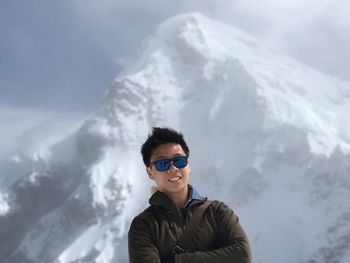 Young man standing against snowcapped mountain