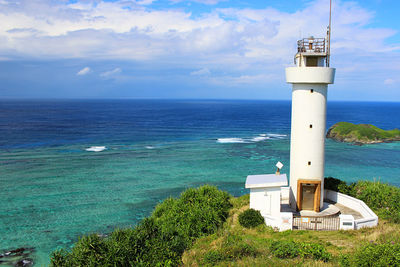 Lighthouse by sea against sky