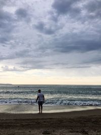 Rear view of man looking at sea against sky