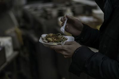 Midsection of man eating food while standing on street