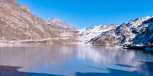 Scenic view of lake and snowcapped mountains against blue sky