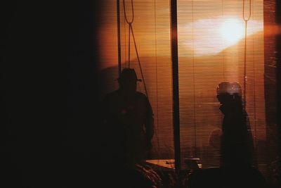 Silhouette people at music concert against sky during sunset