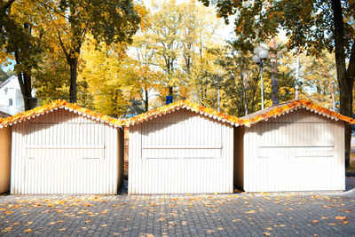 Wooden cottages with fallen leaves on footpath against trees