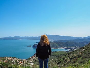 Rear view of woman looking at sea against clear blue sky