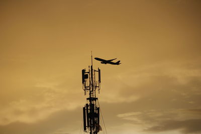 Low angle view of silhouette airplane against sky during sunset