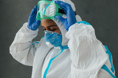 Close-up of young woman wearing protective suit against wall