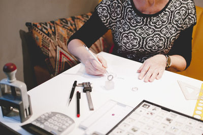 Midsection of senior woman making ring in jewelry workshop