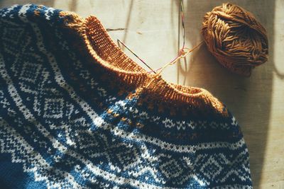 Directly above of knitted sweater with traditional norwegian pattern on wooden table