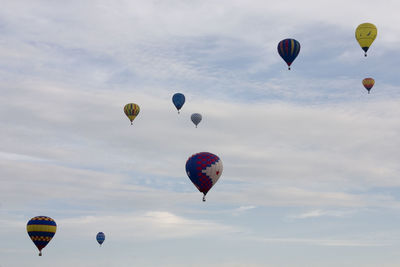 Low angle view of hot air balloons flying in cloudy sky