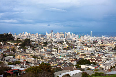 High angle view of city buildings against cloudy sky