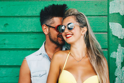 Portrait of young couple standing against wall