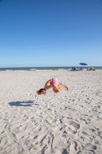 Boy jumping at beach against blue sky