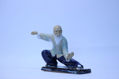 Male figurine performing tai chi against blue background