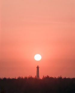 Silhouette tower against orange sky